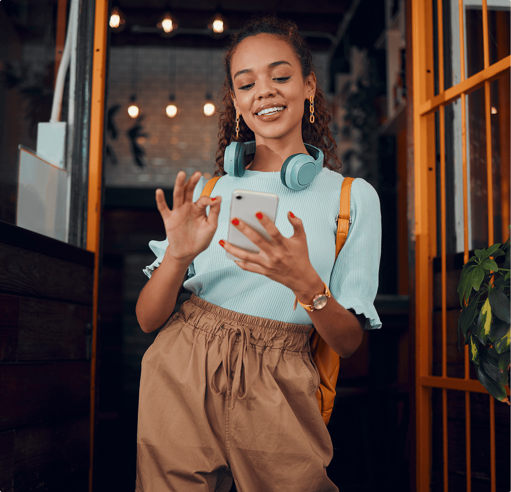 Woman wearing a shirt and pants, with headphones on her head and a smile on her face